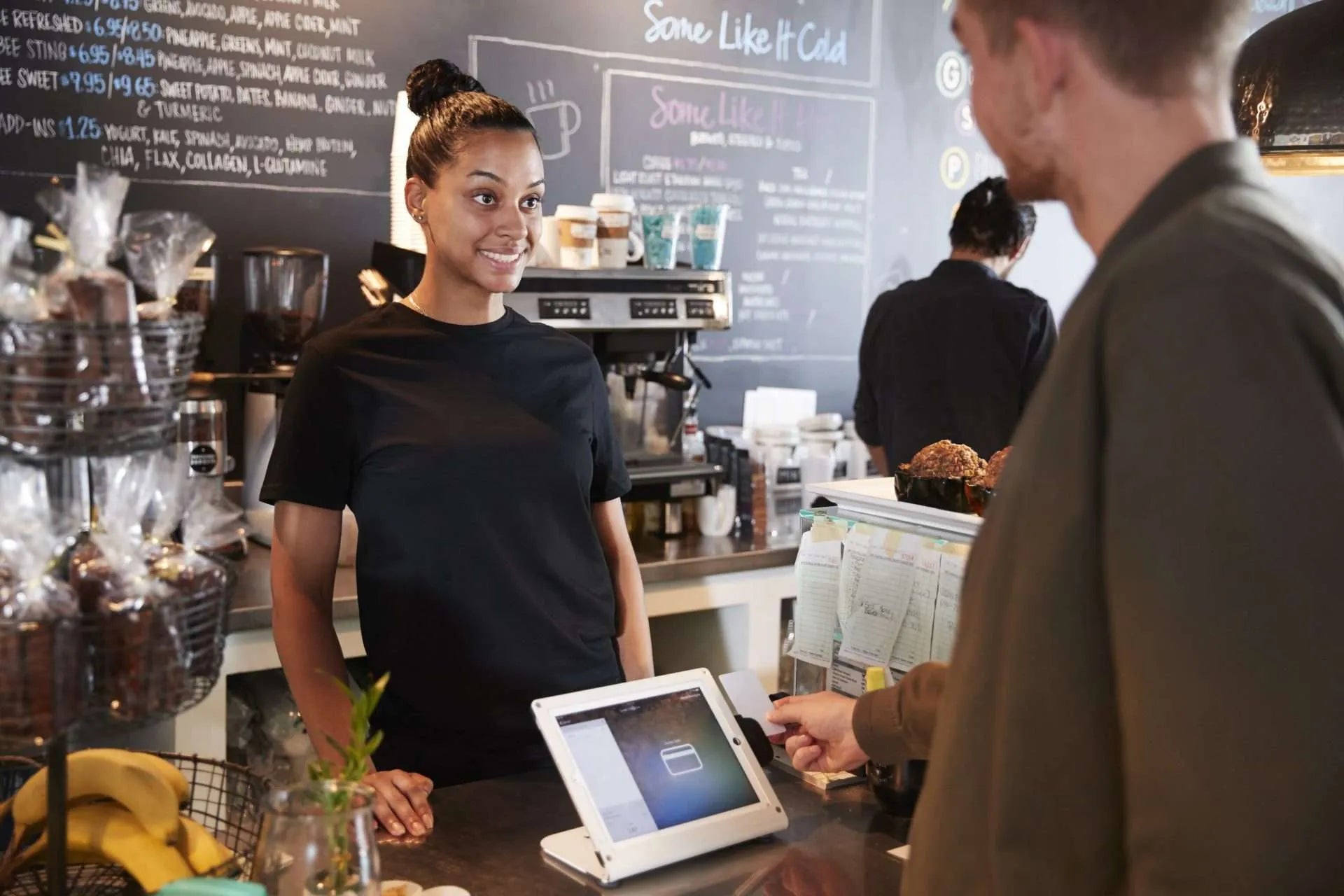 Barista assisting customer using a digital payment system at a café counter
