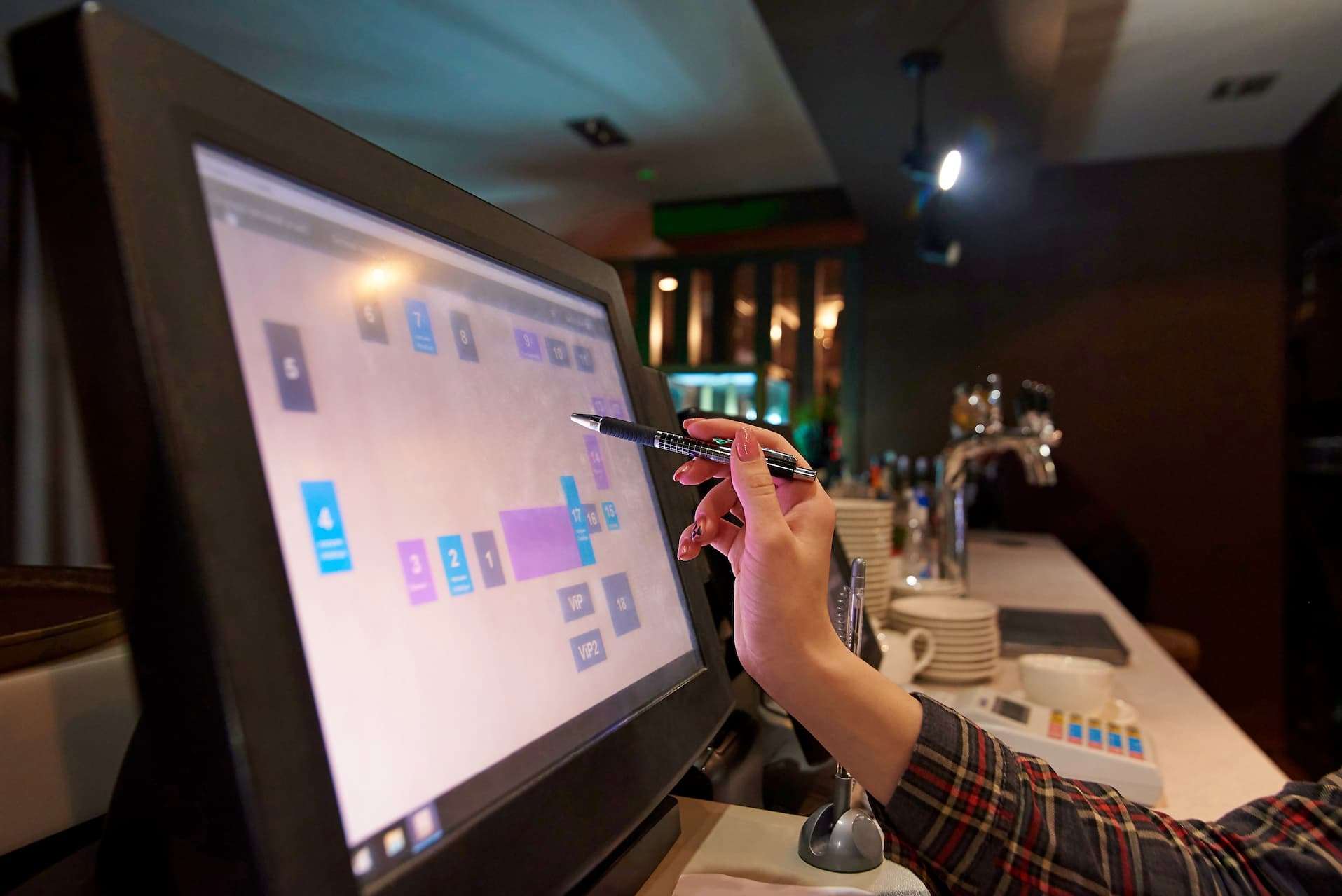 Hand using a pen to point at an anti glare touchscreen in a restaurant